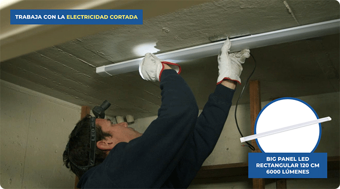 un hombre presenta un panel led rectangular blanco en el cielo de la bodega para marcar sus fijaciones.