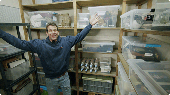 un hombre muy feliz en su bodega de departamento luego de organizarla e iluminar apropiadamente.