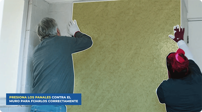 un hombre y una mujer pegan un panel de SPC en el muro de un baño.