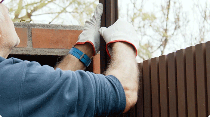 un hombre desliza el último trozo de wall panel 3D en el final del muro exterior.