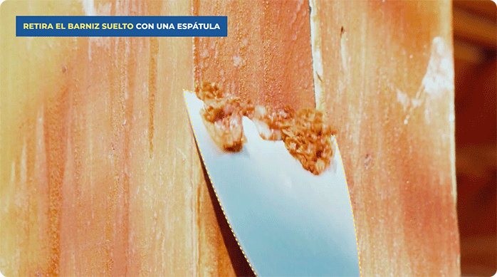 una persona retira el barniz suelto de un pilar de madera usando una espátula.