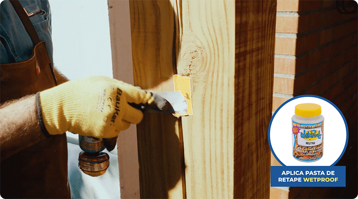 un hombre aplica pasta de retape en las imperfecciones de una viga de madera.