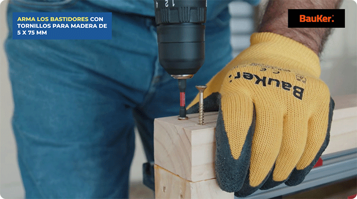 un hombre fija las esquinas de un bastidor con tornillos para madera de 5 x 75 mm.