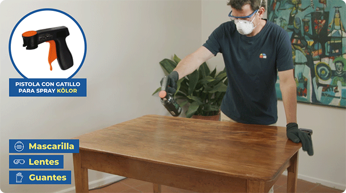 un hombre aplica decapante de pintura en una mesa de madera usando una pistola con gatillo para spray.