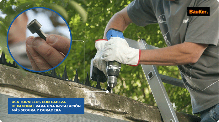 un hombre instala una tira de puntas de protección en un muro de concreto con tornillos con cabeza hexagonal.