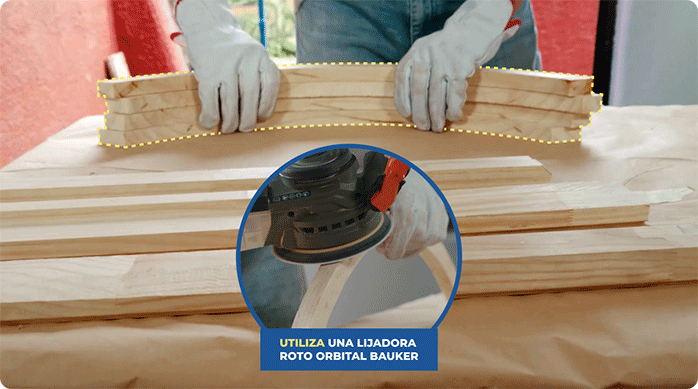 una persona lija los arcos de madera que acaba de cortar para renovar un marco de madera.
