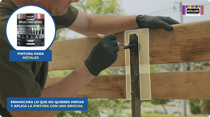 un hombre pinta la estructura metálica de la baranda de madera con pintura para metales.