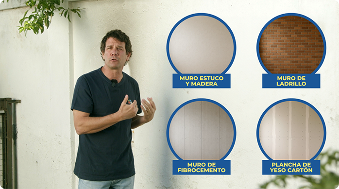 un hombre frente a un muro exterior blanco.