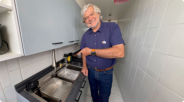 un hombre sonríe y apunta con el dedo el nuevo lavaplatos de Sensi D'acqua que acaba de instalar.