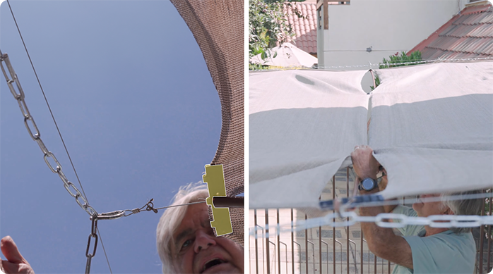 un hombre engancha la malla raschel a los cables principales de la pérgola retráctil con unos ganchos para malla raschel.