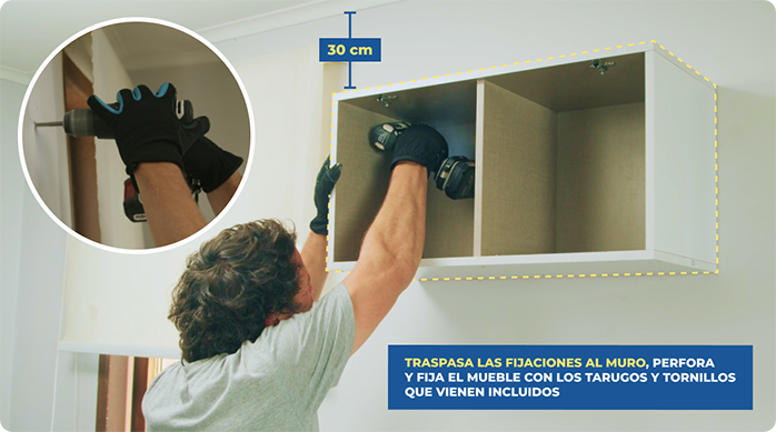 un hombre fija el mueble flotante en la pared con un destornillador inalámbrico.
