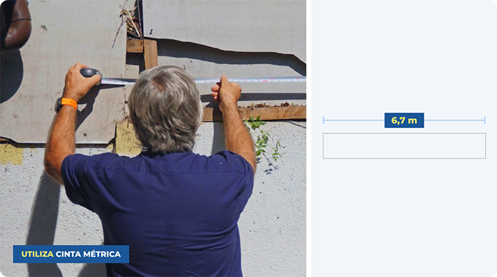 un hombre mide el largo de un muro exterior con una huincha de medir.