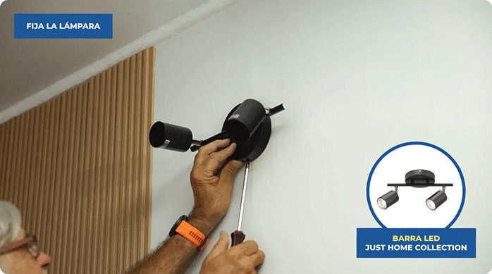 un hombre instala una barra led en una pared interior.