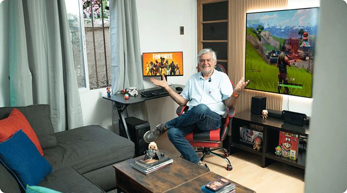 un hombre sentado en una silla gamer en una sala de estar que acaba de renovar al estilo gamer.