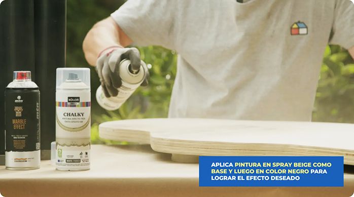 un hombre aplica pintura en spray en la cubierta de la mesa de centro estilo japandi.