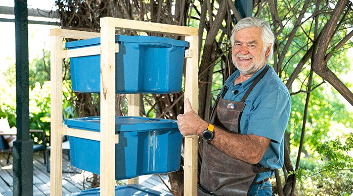 un hombre sonriendo al lado de un mueble para cajas organizadoras que acaba de construir paso a paso.