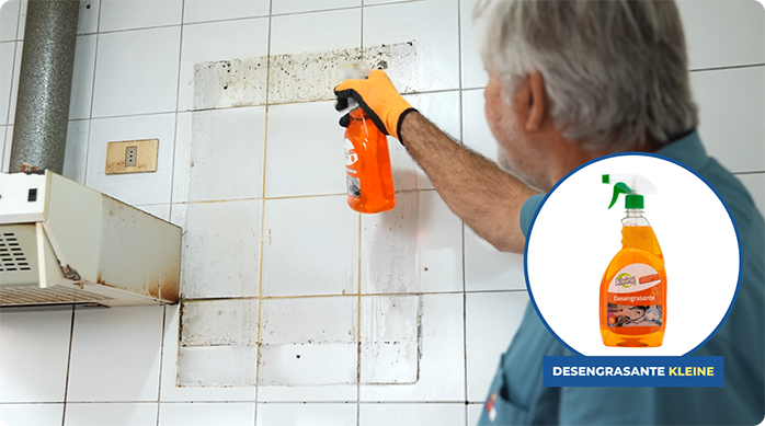 un hombre aplica desengrasante en un muro de cocina sucio.