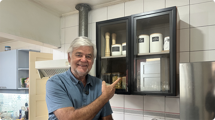 un hombre sonriendo indica con el dedo el mueble flotante que acaba de instalar en el muro de una cocina.