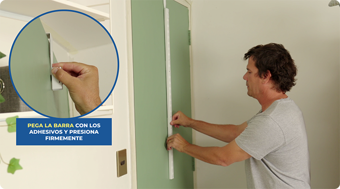 un hombre instala un organizador vertical de metal detrás de una puerta.