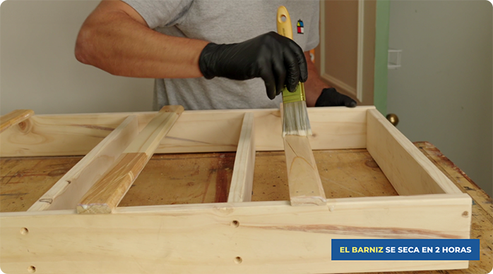 un hombre aplica protector para madera en el organizador vertical.