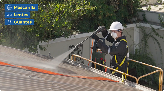 un hombre limpia un techo de zinc con una hidrolavadora.