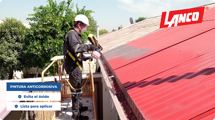 un hombre en un andamio pinta un techo de zinc con la pintura anticorrosiva de la marca Lanco.