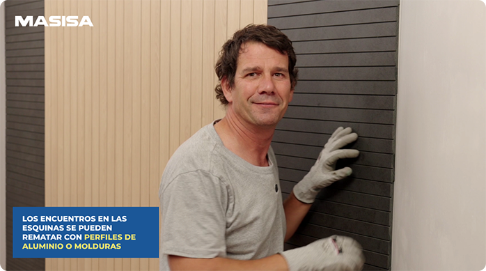 un hombre sonriendo frente al muro de dormitorio que acaba de renovar con revestimientos micro ripados Masisa.