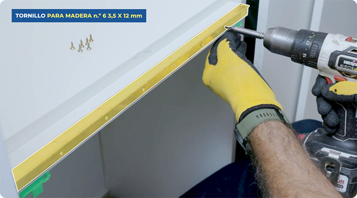 una persona instala una bisagra piano en un tablero de melamina.
