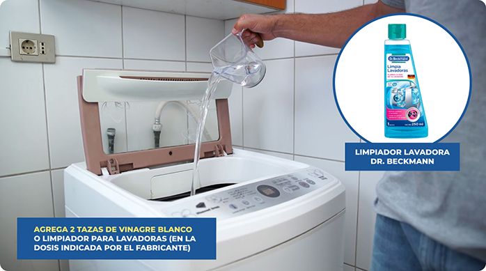 una persona vierte vinagre blanco en el tambor de la lavadora para limpiarlo.