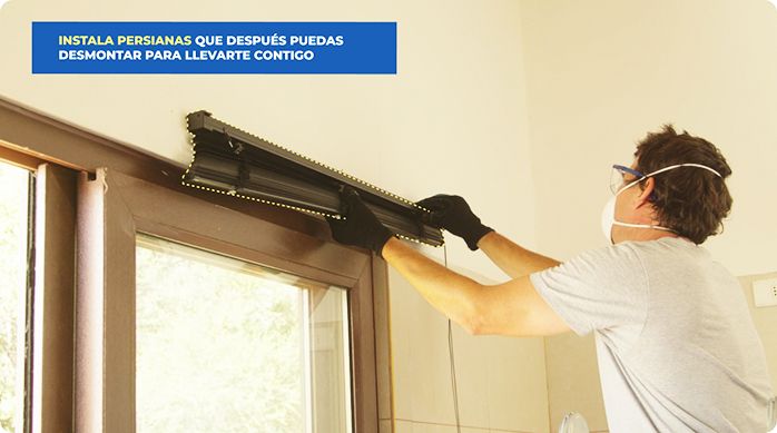 un hombre instala una persiana en la ventana de una cocina.