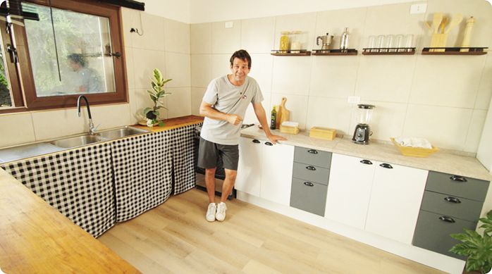 un hombre feliz en una cocina arrendada que acaba de renovar con elementos simples.