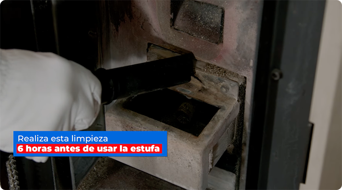 un hombre limpia los pulmones de una estufa a pellet con una aspiradora.