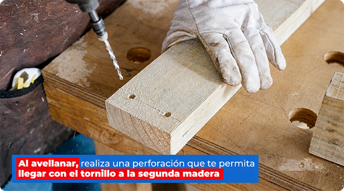 un hombre hace perforaciones con una broca para madera en un listón de pino seco cepillado.