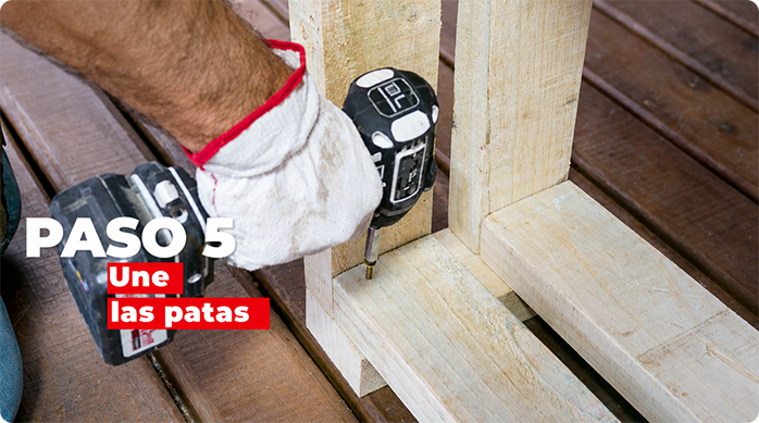 un hombre atornilla las patas del leñero exterior.