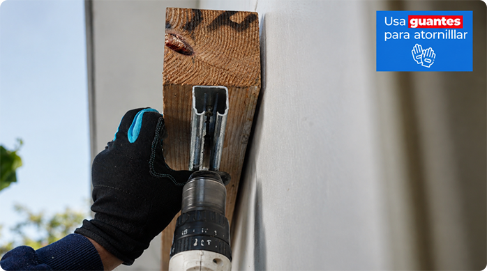un hombre fija un riel de corredera en la viga de madera sobre la ventana.