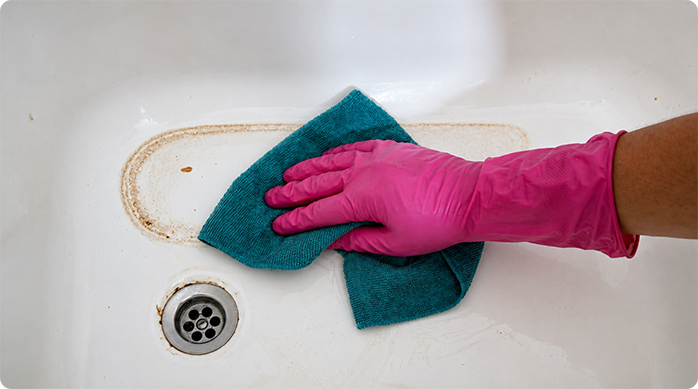 una persona pasa un paño para limpiar el fondo de una tina de baño.