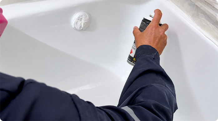 un hombre aplica pintura especial para bañeras o tinas, para renovar la tina de un baño.