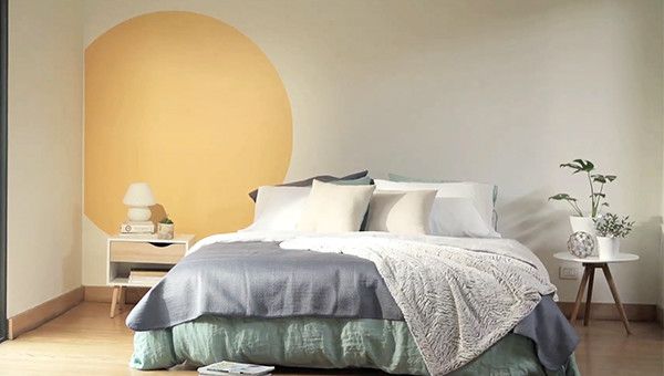 un muro interior pintado con figuras geométricas con una mesa de arrimo y una silla